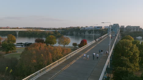 Luftaufnahmen-Während-Des-Sonnenuntergangs,-Die-Zwei-Läufern-Folgen,-Die-Die-Walnut-Street-Bridge-Hinauflaufen,-Um-Den-Tennessee-River-In-Chattanooga,-Tennessee,-Zu-überqueren