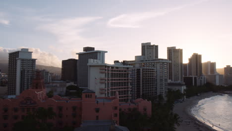 Schwenk-über-Hotel--Und-Resortgebäude-Mit-Blick-über-Die-Bucht-Von-Waikiki-Bei-Sonnenaufgang,-Diamond-Head-In-Der-Ferne,-Hawaii