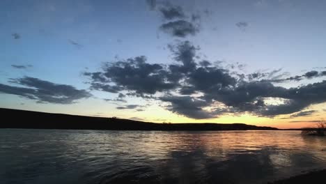 Timelapse-of-a-river,-post-storm,-with-clouds,-sunset-colors,-and-tranquil-flow