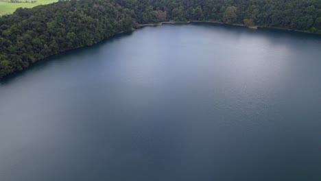 Serene-Water-Of-Lake-Eacham-In-Atherton-Tableland,-Queensland,-Australia---aerial-drone-shot