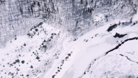 4K-Extrem-Breite-Top-Down-Aufnahme-Von-Langläufern,-Die-Am-Rand-Eines-Schneebedeckten-Flusses-In-Einem-Weißen-Winter-Quebec,-Kanada,-Entlangfahren