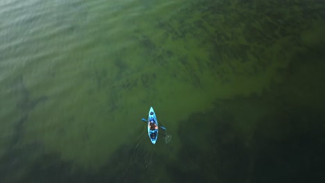 Aerial-view-of-a-man-kayaking-clear-waters-in-Oregon,-Diamond-Lake