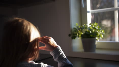 Close-Up-Medium-Video-of-7-Year-Old-Sunlit-Girl-by-the-window-longing-for-outside-play