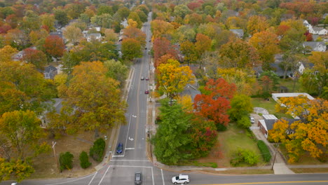 Flying-over-street-in-Kirkwood-following-cars-as-they-drive-through-tree-lined-streets-in-Fall-on-a-pretty-day