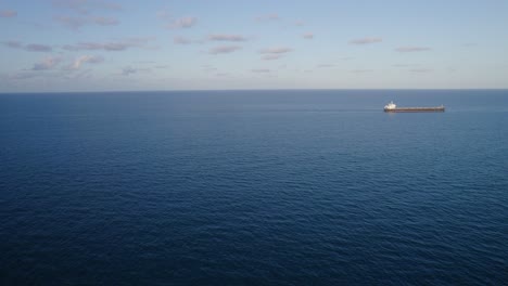 Distant-View-of-Shipping-Vessel-In-The-Open-Sea-At-Sunrise-In-North-Queensland,-Australia