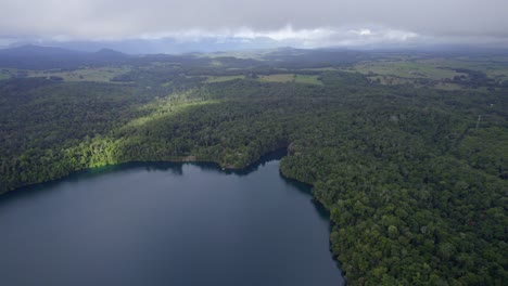 Exuberante-Selva-Tropical-Que-Rodea-El-Lago-Eacham-En-Atherton-Tableland,-Queensland,-Australia---Toma-Aérea