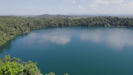 Sky-Reflection-On-The-Calm-Waters-Of-Lake-Eacham-In-Queensland,-Australia---aerial-drone-shot