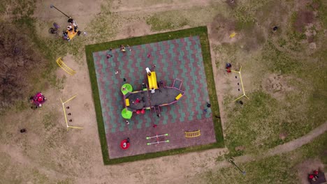 A-dynamic-pivoting-aerial-footage-of-kids-playing-around-the-children's-playground-with-swings-and-a-sailing-ship-styled-kiddie-slide-at-the-center