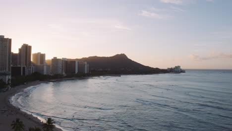 Sunrise-Over-Diamond-Head-and-Highrise-Hotel-Buildings,-Light-Rays-reflecting-on-Sea,-Waikiki