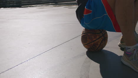 Detailaufnahme-Eines-Jungen-Mannes-Auf-Einem-Basketball-Auf-Einem-Straßenbasketballplatz-Mit-Einer-Untergehenden-Sonne-Mit-Einem-Schönen-Licht,-In-Barcelona,-Spanien