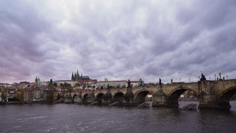 Charles-Bridge-or-Karluv-most-in-Prague,-side-panning-left-view,-moving-clouds-and-Vltava-river