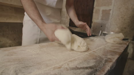 A-baker-is-quickly-folding-and-kneading-some-dough-in-a-bakery