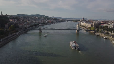 Drone-shot-of-Danube-River-in-Budapest-with-bridge-and-boat