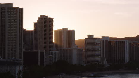 Brilliant-Sunlight-Bloom-Through-Highrise-Hotels-on-Kuhio-Beach,-Waikiki,-Medium-Shot