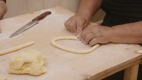 Slow-motion-footage-of-a-lady-in-italy-rolling-dough-to-make-pasta-shells-and-cutting-the-roll
