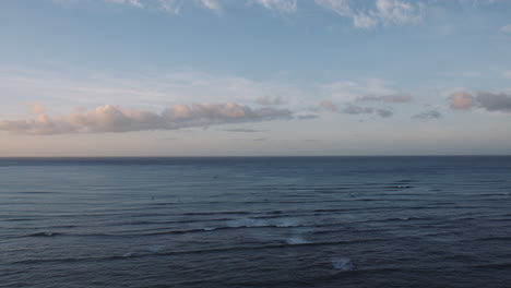Early-Morning-Surfers-Riding-the-Waves-on-Waikiki-Bay,-Coastal-Horizon-and-Colorful-Sunrise,-Hawaii