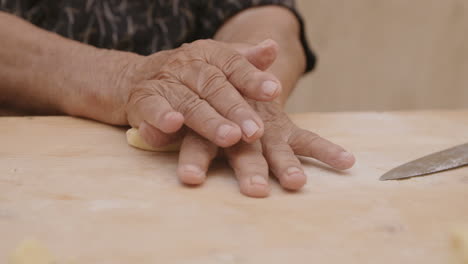 Die-Hände-Einer-Alten-Frau,-Die-In-Italien-Nudelteig-Rollen,-Um-Ihn-Zu-Muscheln-Zu-Verarbeiten