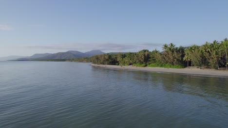View-From-Coral-Sea-Of-Palm-Trees-And-Tourists-On-The-Shore-Of-Four-Mile-Beach-During-Summer-In-Port-Douglas,-Queensland
