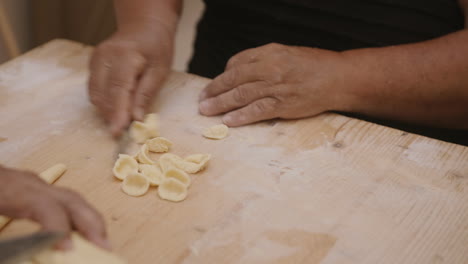 Slow-motion-footage-of-an-old-lady-cutting-and-rolling-pasta-dough-into-conchiglie-shells-in-Bari,-Italy