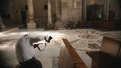 Researcher-in-a-church-in-Italy-taking-a-photograph-of-the-sunset-light-shining-through-a-window-in-slow-motion