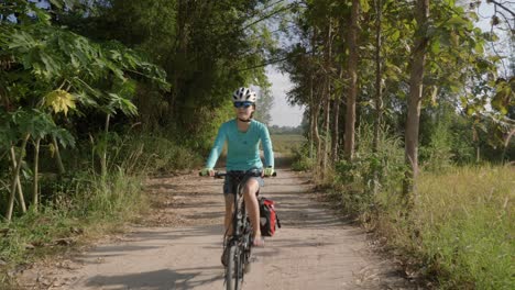 Una-Filmación-Estacionaria-De-Una-Ciclista-Montando-Su-Bicicleta-A-Lo-Largo-De-Una-Calle-Vacía-En-Isan,-Tailandia