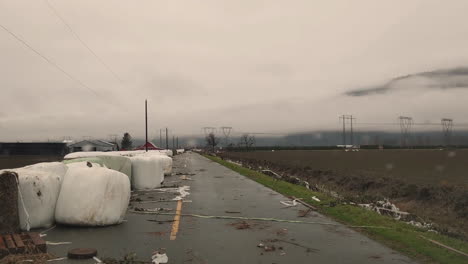 Hay-Bales-In-Damaged-Plastic-Wrap-Cover-Scattered-On-The-Road-After-Flooding-In-Abbotsford,-BC,-Canada