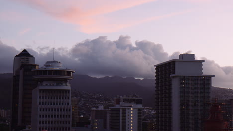 Tops-of-Highrise-Buildings-towards-Downtown-Waikiki-at-Sunrise-with-Mountains-in-Background,-Hawaii,-Handheld