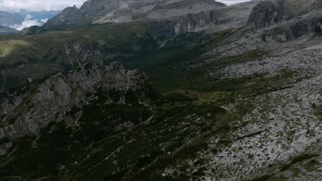 Aerial-tilt-up-shot-of-green-valley-with-hiker-path-in-gigantic-mountains-of-Dolomites---Beautiful-summer-day-in-nature