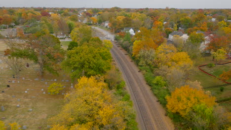 Aerial-view-following-train-tracks-through-Kirkwood-neighborhood-in-Autumn-at-peak-color