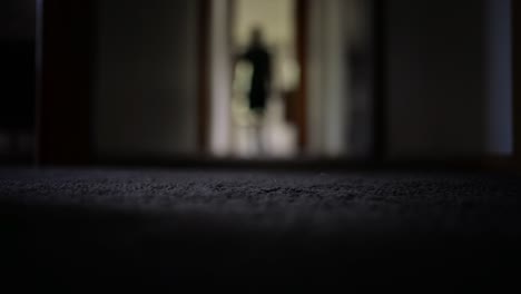 Person-walking-through-dark-carpeted-hallway-at-home