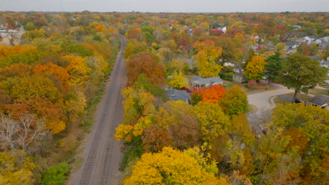 Aerial-over-train-tracks-and-trees-at-peak-color-in-Autumn-in-a-residential-neighborhood-in-Kirkwood-in-St