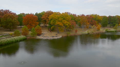 Aerial-over-a-pond-in-Kirkwood-park-and-towards-a-row-of-trees-at-peak-Fall-color-on-a-beautiful-day