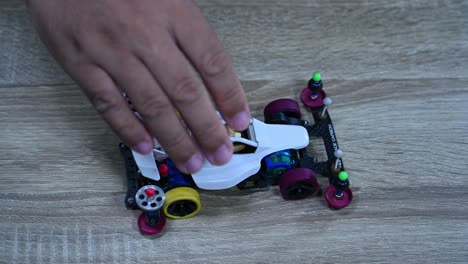 A-hand-dropping-the-Tamiya-Mini-4WD-four-times-on-the-table,-Hobby,-mini-4WD-racing