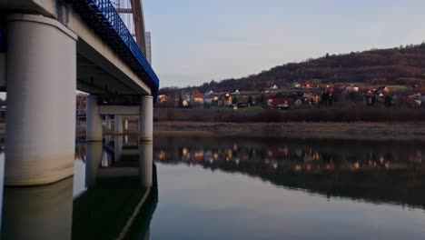 Drohnen-Fliegen-Unter-Der-Eisenbahnbogenbrücke-über-Das-Ruhige-Wasser-Des-Flusses