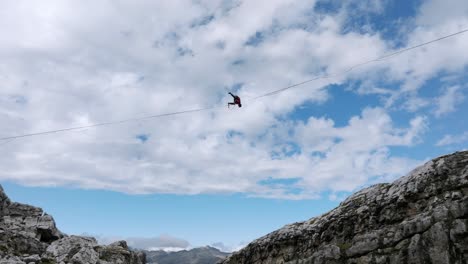 Extreme-sport-of-man-jumping-on-slackline-in-mountains-making-tricks-and-having-fun---aerial-tilt-up-shot
