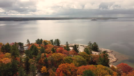 Aerial-view-of-a-calm-bay-with-banks-full-of-colorful-autumn-trees