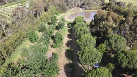 Drone-aerial-parallax-over-lush-permaculture-farm-with-dam-and-a-campervan