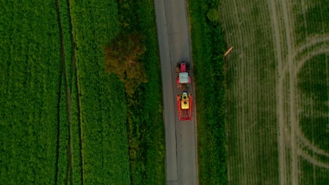 Traktor-Fährt-Auf-Asphalt-Zwischen-Landwirtschaftlichen-Straßen---Drohnenaufnahme-Von-Oben-Nach-Unten