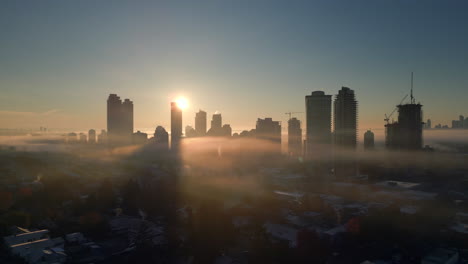 Skyscrapers-with-Sun-rise-shooting-through-them-in-a-city-of-fog