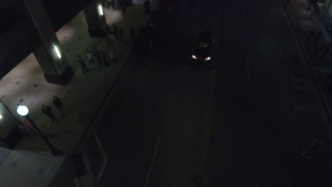 Aerial-shot-of-a-car-waiting-in-the-middle-of-a-street-at-night-in-downtown-Georgia