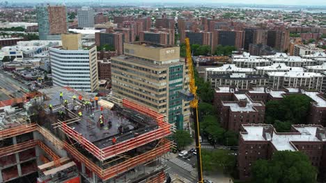 Orbiting-a-crane-lifting-construction-materials-to-a-city-project-site---aerial-view