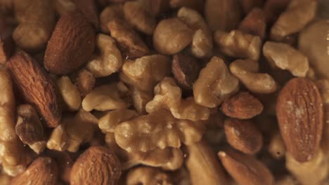 Close-up-shot-of-different-varieties-of-nuts-spinning-in-glass,-walnut,almond,cashew-nuts