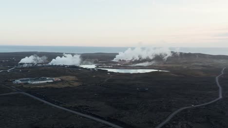 Volcanic-landscape-on-Reykjanes-peninsula-with-distant-power-plant,-aerial