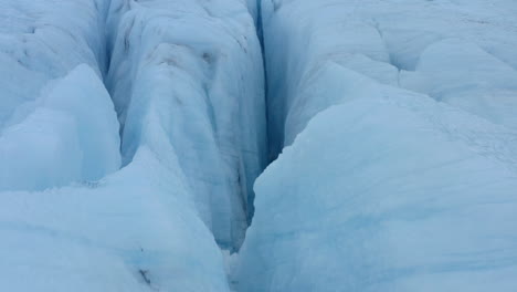 Slow-aerial-shot-looking-into-deep-crevasses-in-thick-ice-glacier