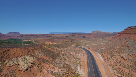 Ascending-drone-shot-of-Long-road-running-through-Mount-Zion-with-mountain-range-in-the-background-located-in-Southern-Utah