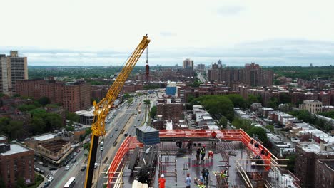 Aerial-view-of-a-crane-lifting-rebar-to-the-top-of-a-building-in-Queens,-NY-USA