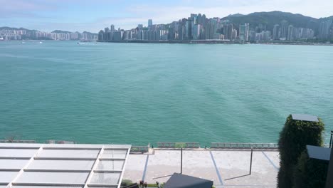 Ein-Fußgänger-Geht-Durch-Die-Victoria-Harbour-Waterfront,-Während-Sie-Den-Abend,-Den-Sonnenuntergang-Und-Den-Blick-Auf-Die-Skyline-Der-Wolkenkratzer-Der-Insel-Hong-Kong-Genießen