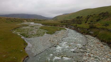 Small-creek-flowing-through-a-bigger-river-bed-coming-from-the-mountains-in-Mackenzie,-New-Zealand