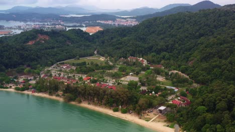 Aerial-landscape-shot-of-tourist-destination-teluk-batik-beach-surrounded-by-green-jungle-forest-and-hilly-mountain-at-Lumut,-Perak,-Malaysia,-Southeast-Asia
