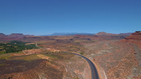 Static-Drone-shot-of-cars-driving-down-a-winding-road-near-Mount-Zion-with-mountain-range-in-the-background-located-in-Southern-Utah
